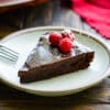 slice of flourless chocolate cake topped with raspberries and powdered sugar