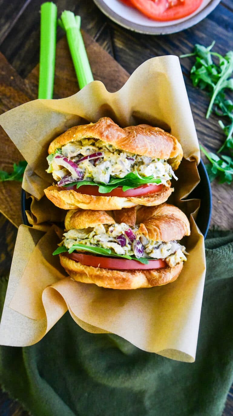 two croissant chicken salad sandwiches face up in a bowl