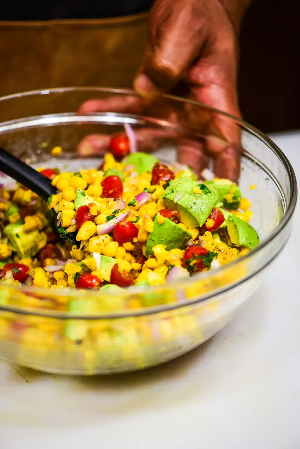 mixing corn and avocado salsa ingredients' together