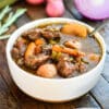 chuck beef stew in a white bowl with potatoes and carrots
