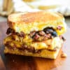brisket grilled cheese sandwich cut in half on a wooden cutting board
