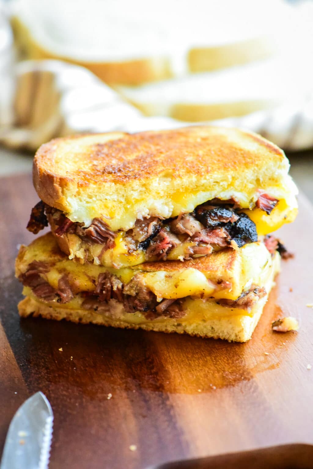 brisket grilled cheese sandwich cut in half on a wooden cutting board