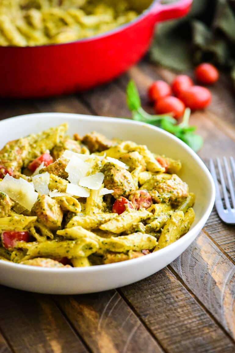 individual serving bowl of creamy pesto pasta topped with shaved parmesan