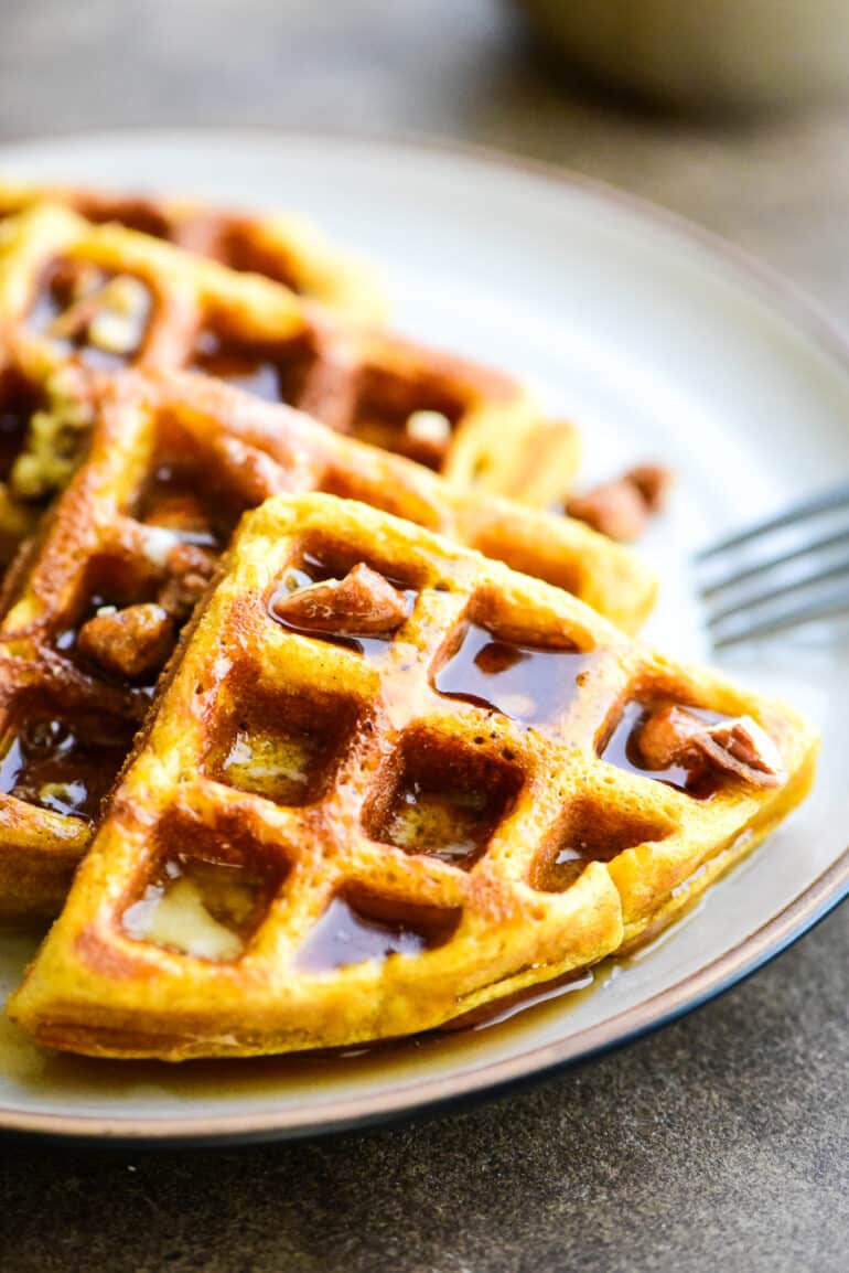 pumpkin waffles topped with butter, pecans, and maple syrup