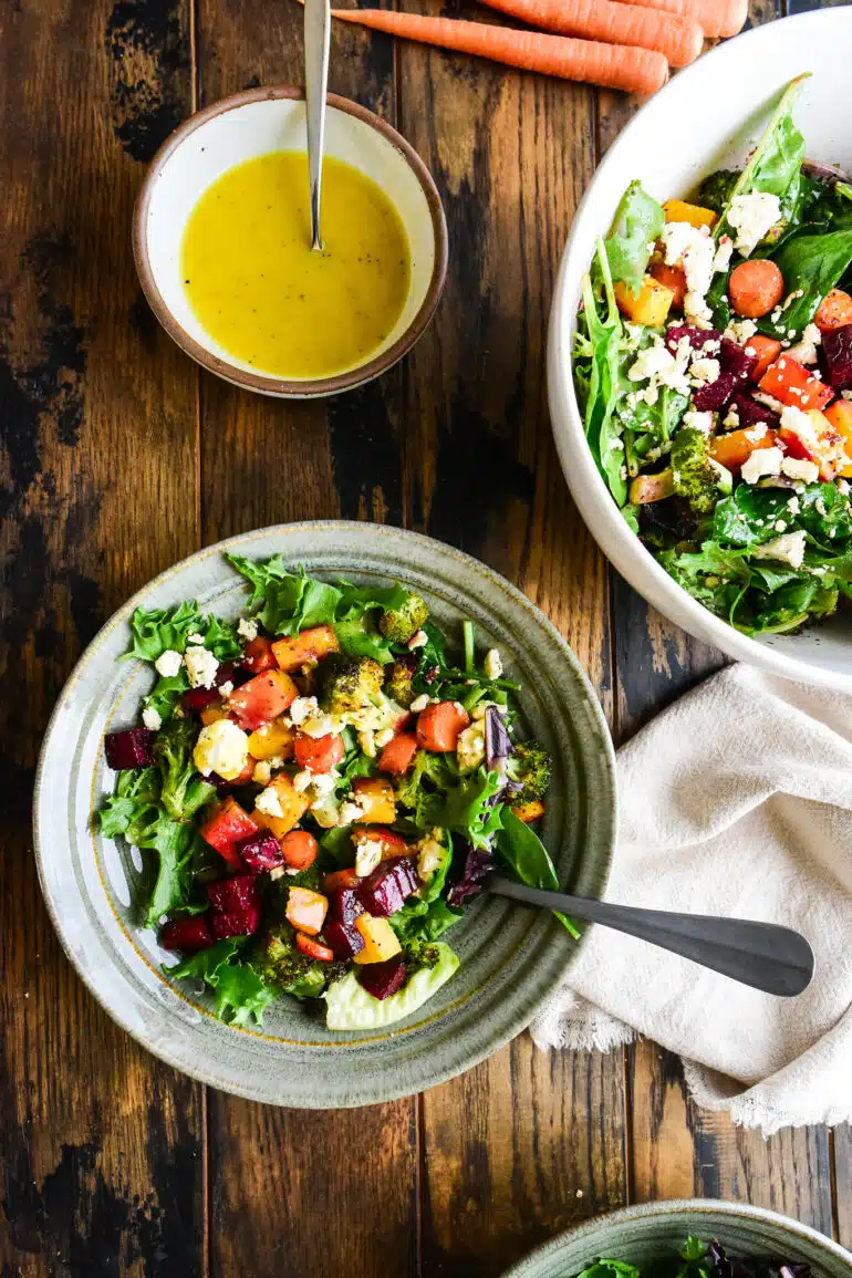 two bowls of roasted veggie salad with a side of honey mustard vinaigrette.