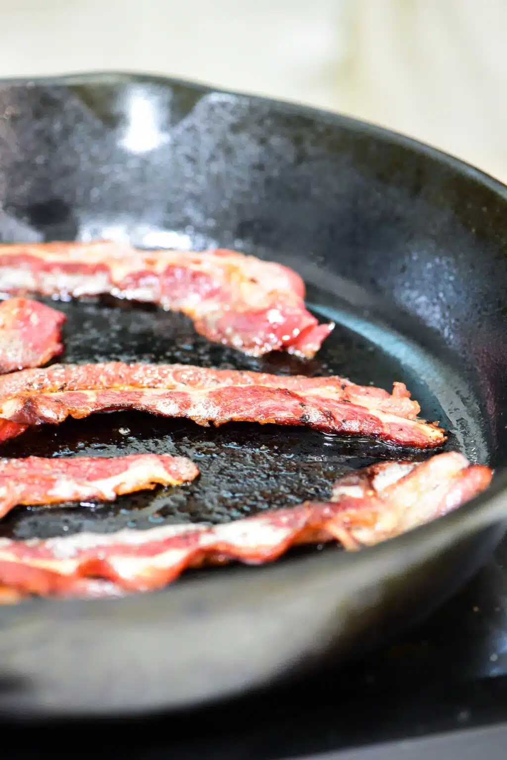 cooking beef bacon in a cast iron skillet