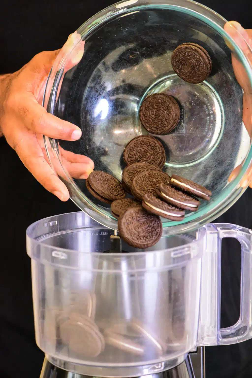 adding oreo cookies to a food processor to crumble them