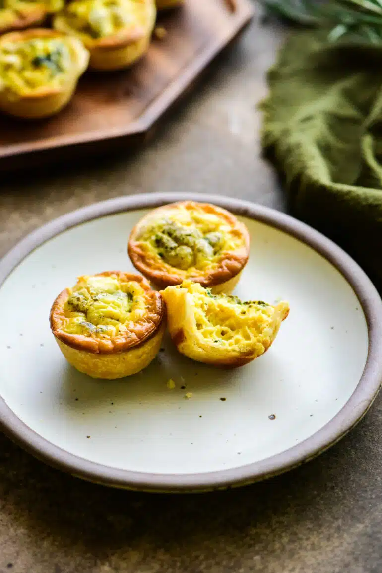 3 mini quiche on a appetizer plate with one bitten out of