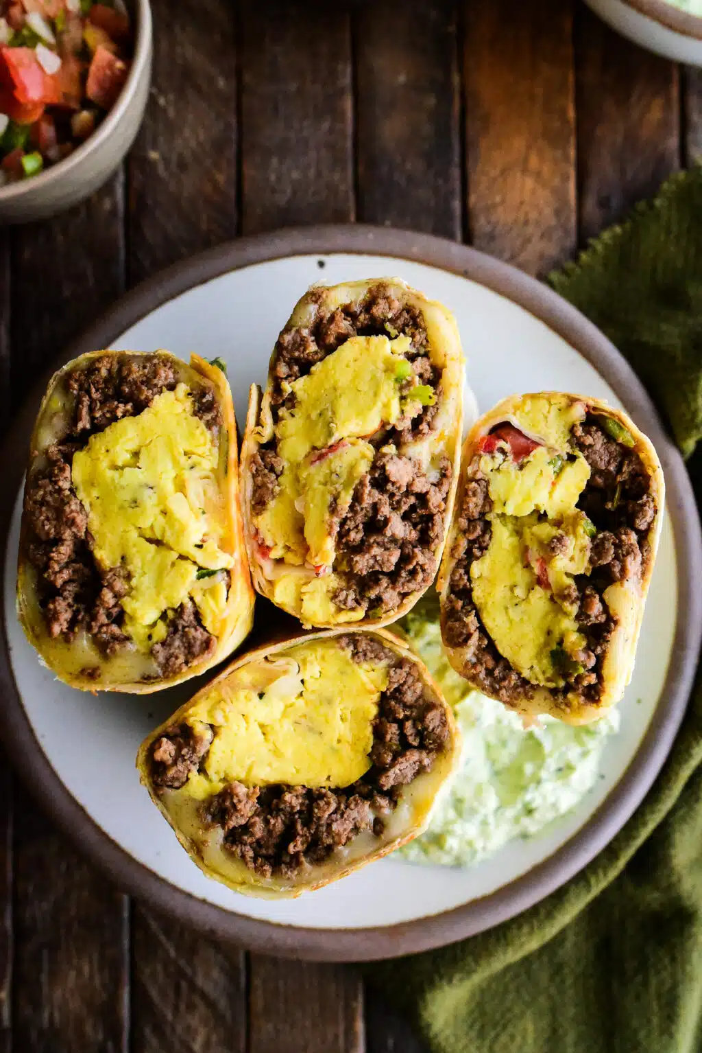 over head shot of beef breakfast burritos in a bowl cut side facing up