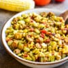 bowl of vegetarian succotash with whole corn and tomatoes in the background