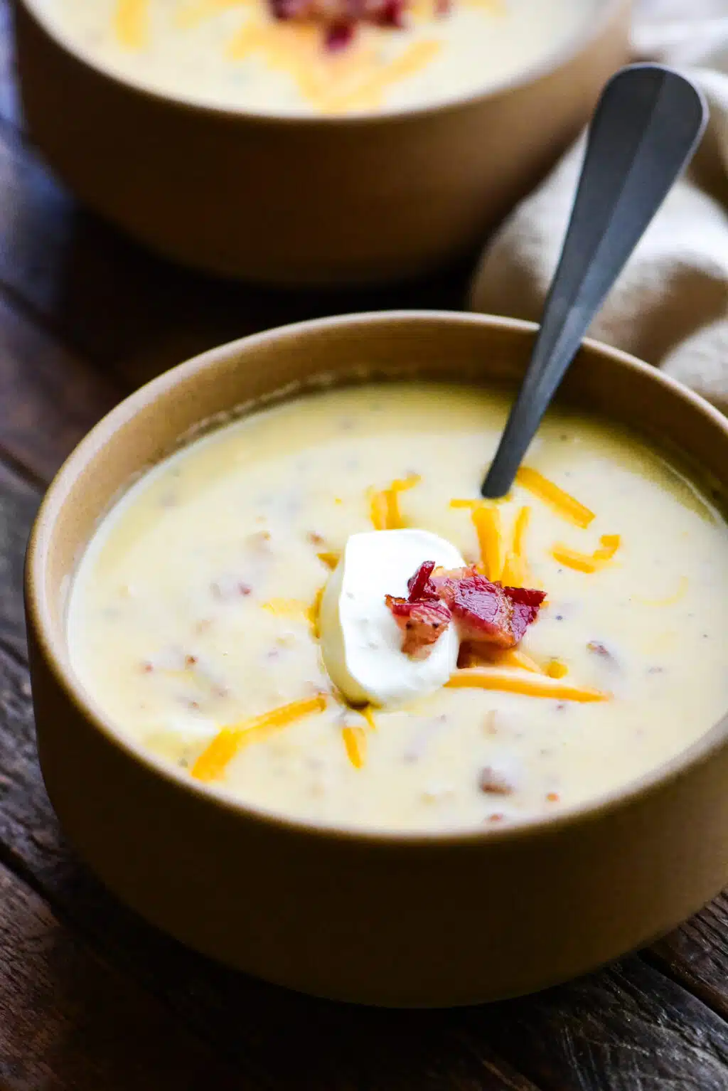 bowl of baked potato soup topped with shredded cheese and bacon
