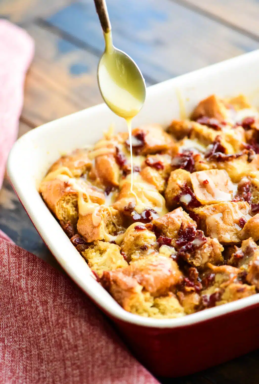 Drizzling maple sauce on the baked maple bacon bread pudding