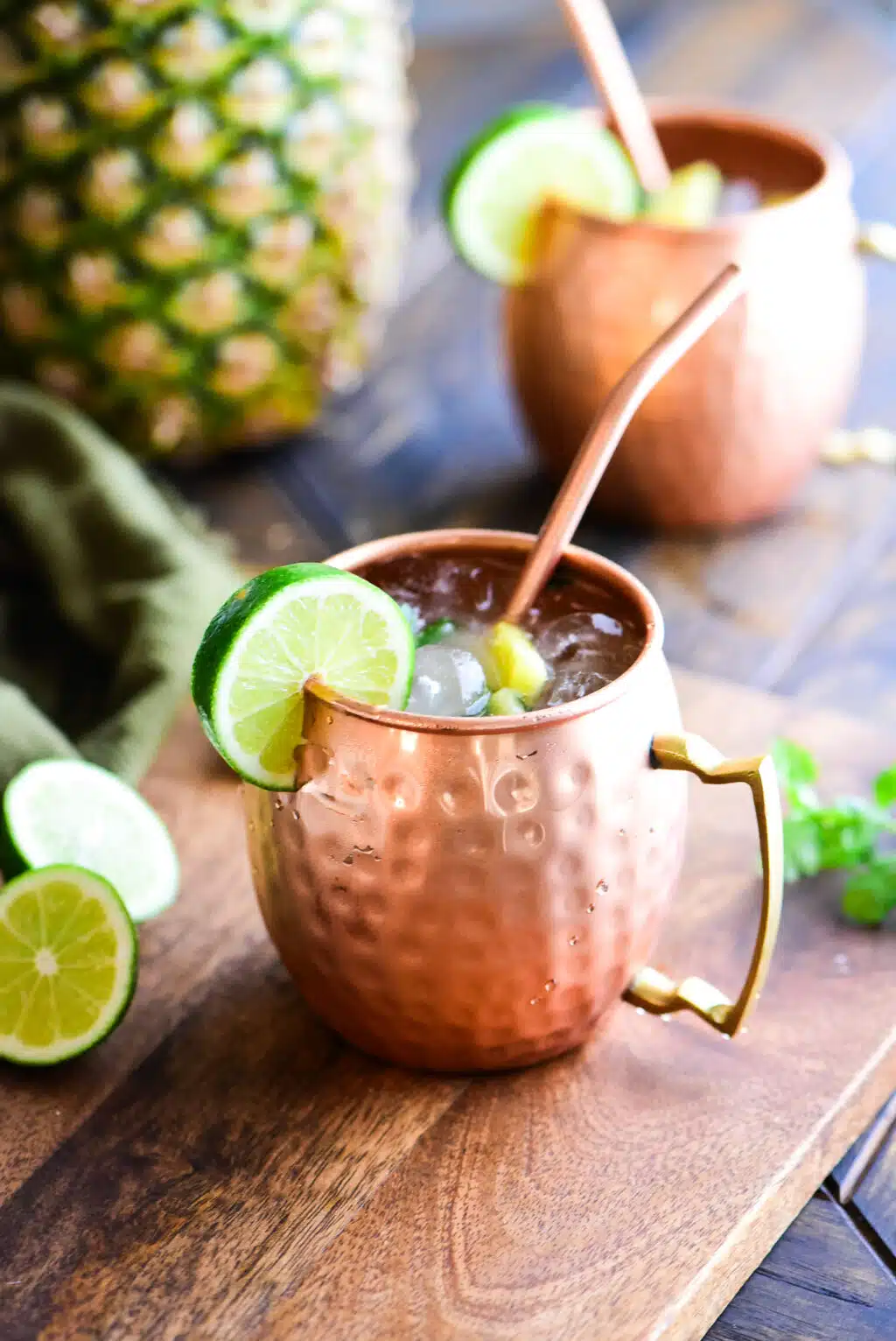 Pineapple Moscow Mule served in a copper mug with a copper straw and garnished with a lime.