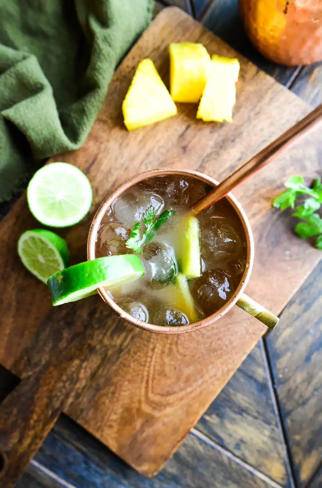 Overhead shot of a Pineapple Moscow Mule served in a copper mug with a copper straw and garnished with a lime.