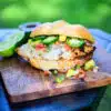 Sweet & Spicy Honey Grilled Chicken Sandwich served on a cutting board next to a grill