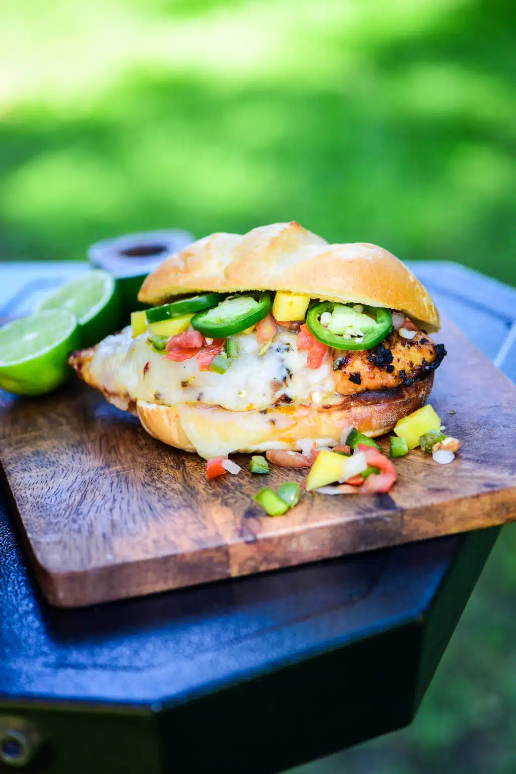 Sweet & Spicy Honey Grilled Chicken Sandwich served on a cutting board next to a grill