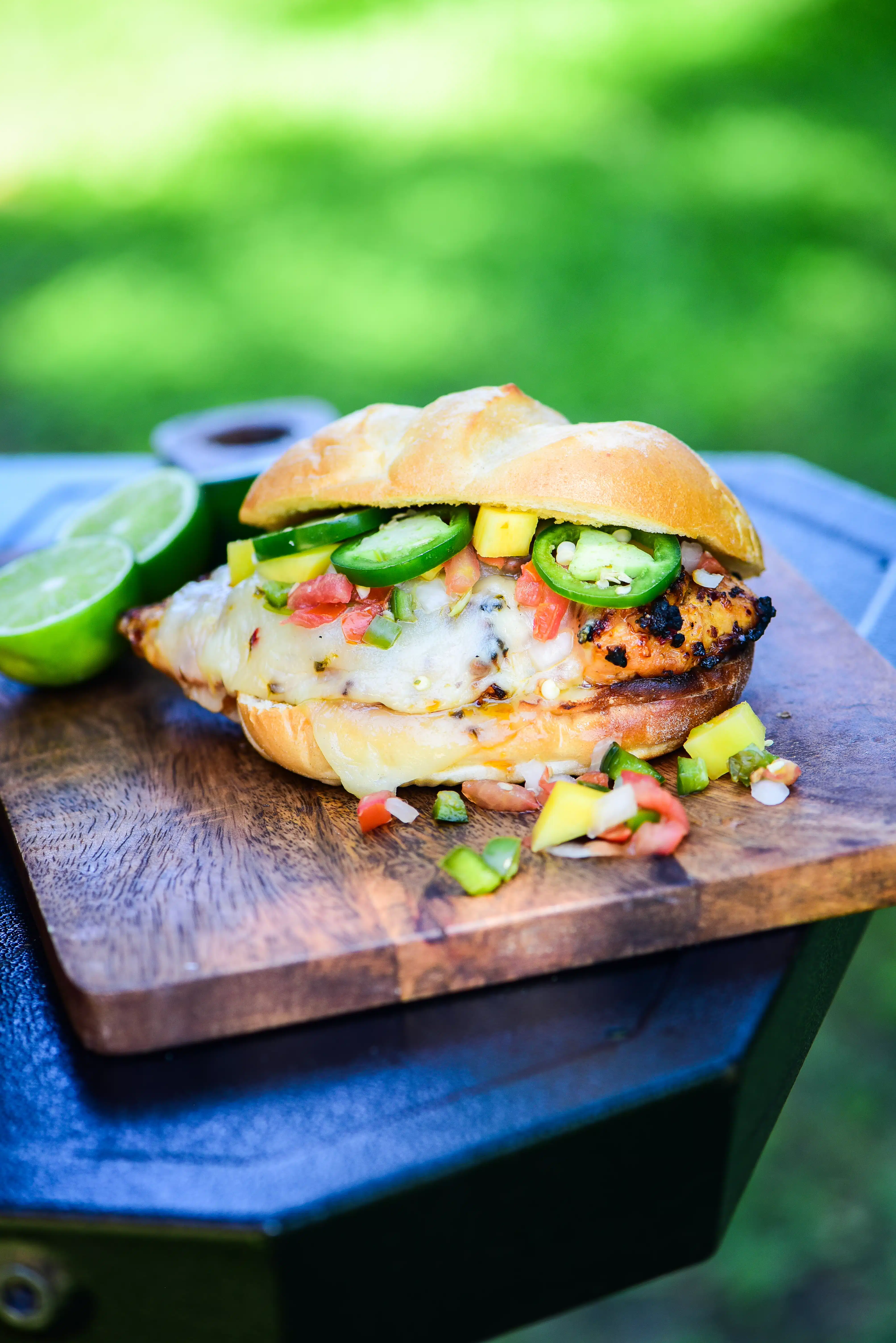 Sweet & Spicy Honey Grilled Chicken Sandwich served on a cutting board next to a grill