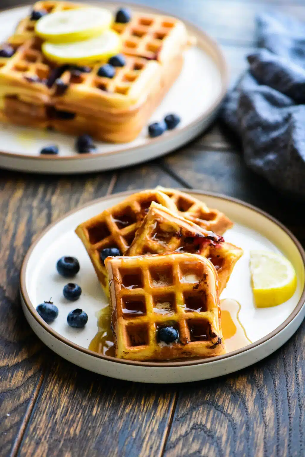 plate of lemon blueberry waffles drizzled with maple syrup