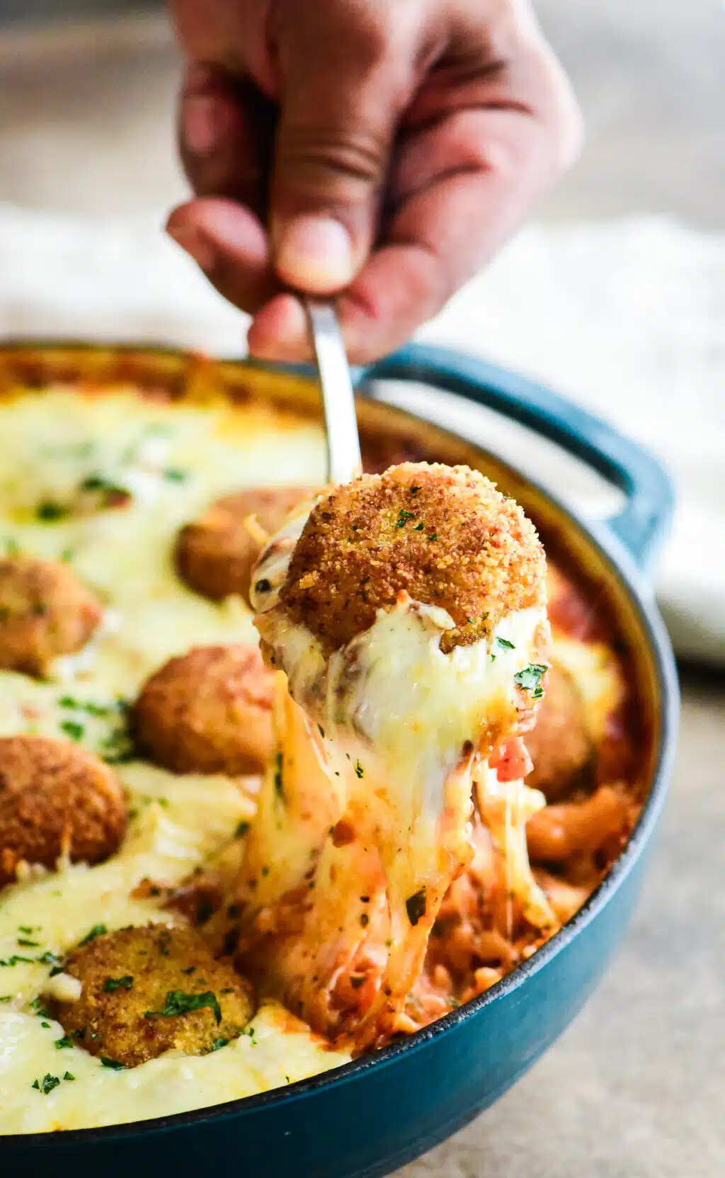 cheese pull from pulling meatballs from the skillet of orzo