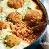 large skillet of chicken parmesan meatball orzo with a serving scooped out.