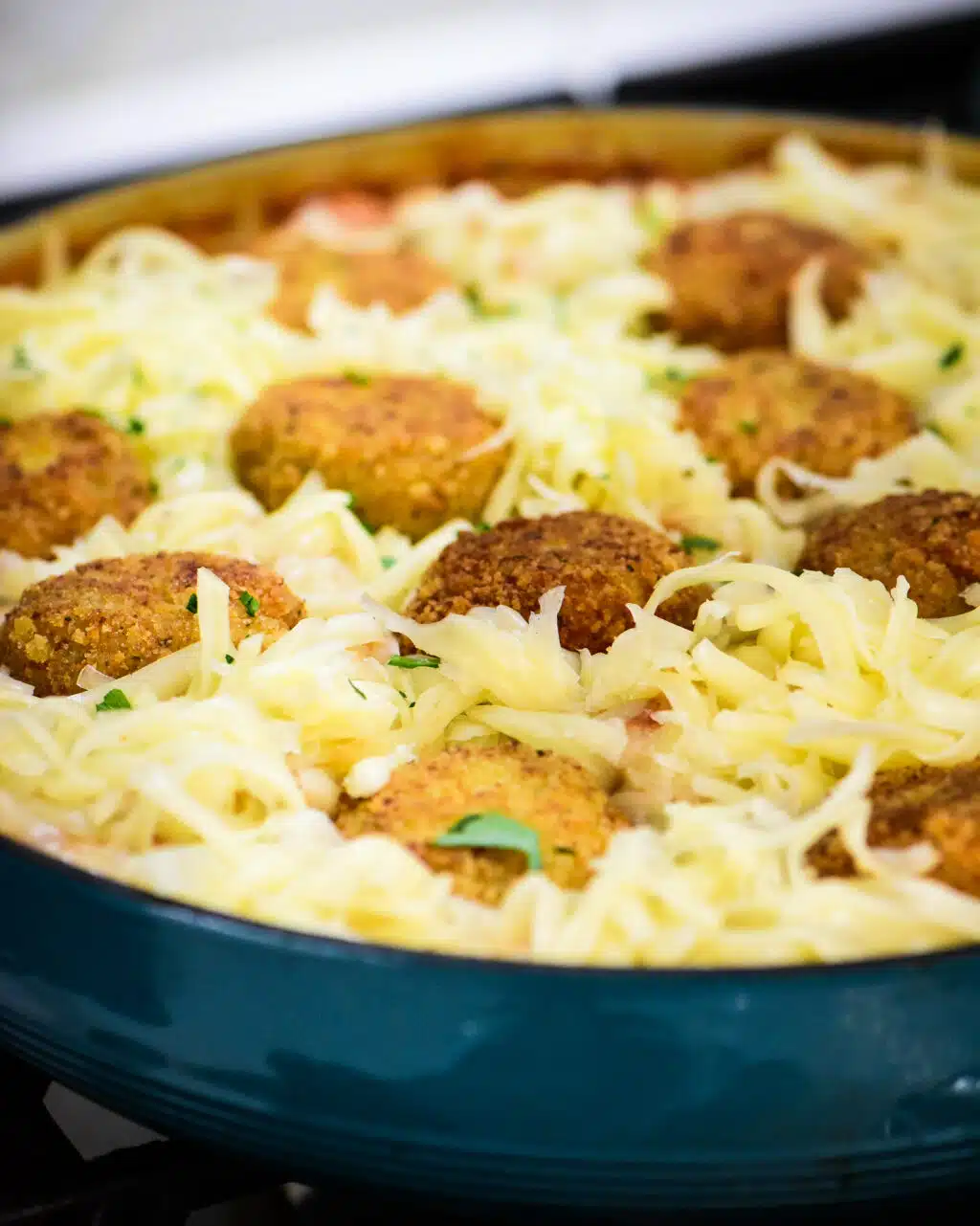 skillet with meatballs and orzo topped with mozzarella cheese