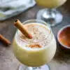 close up shot of a puerto rican coquito cocktail garnished with a cinnamon stick