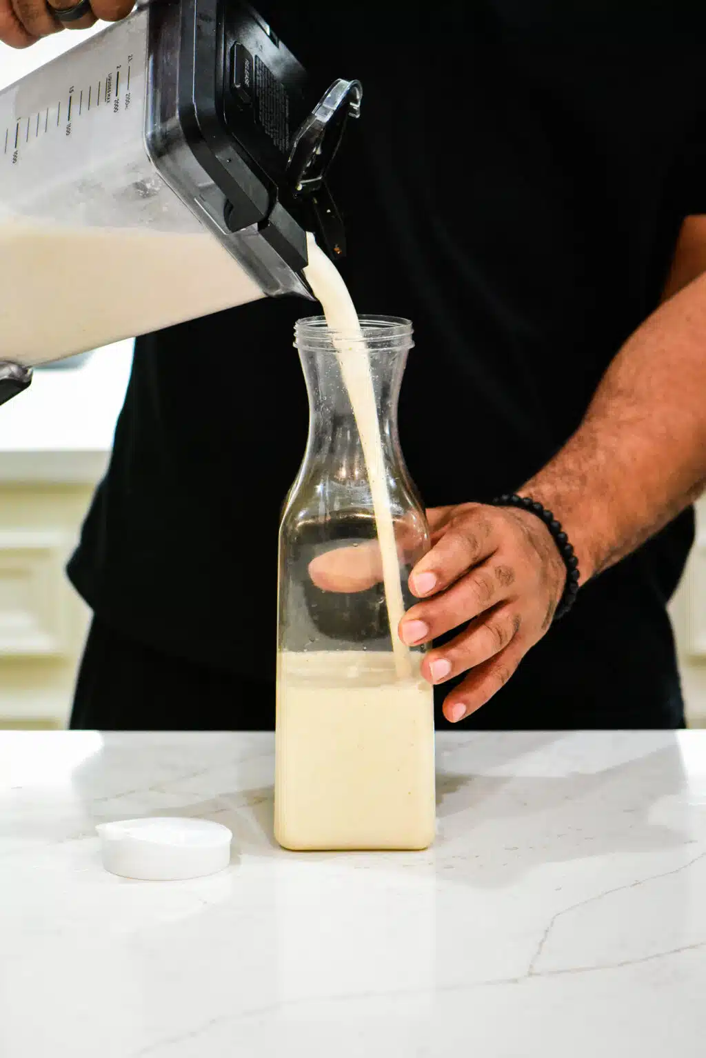 pouring blended coquito into a container to refrigerate