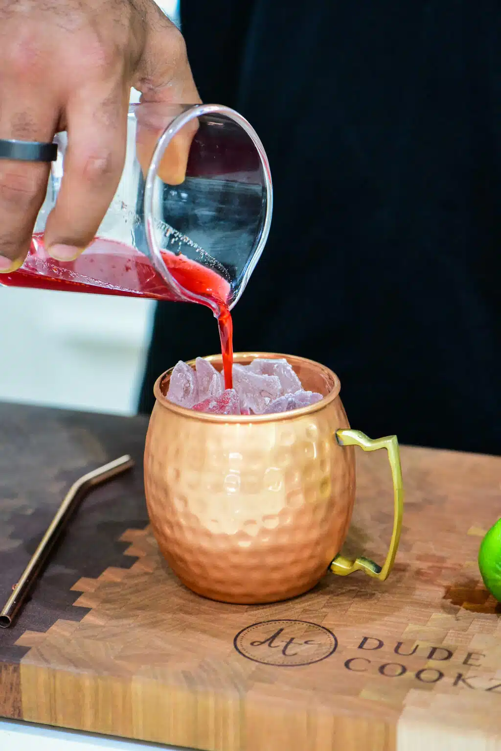 adding strained cocktail mixture to the copper mug filled with ice.