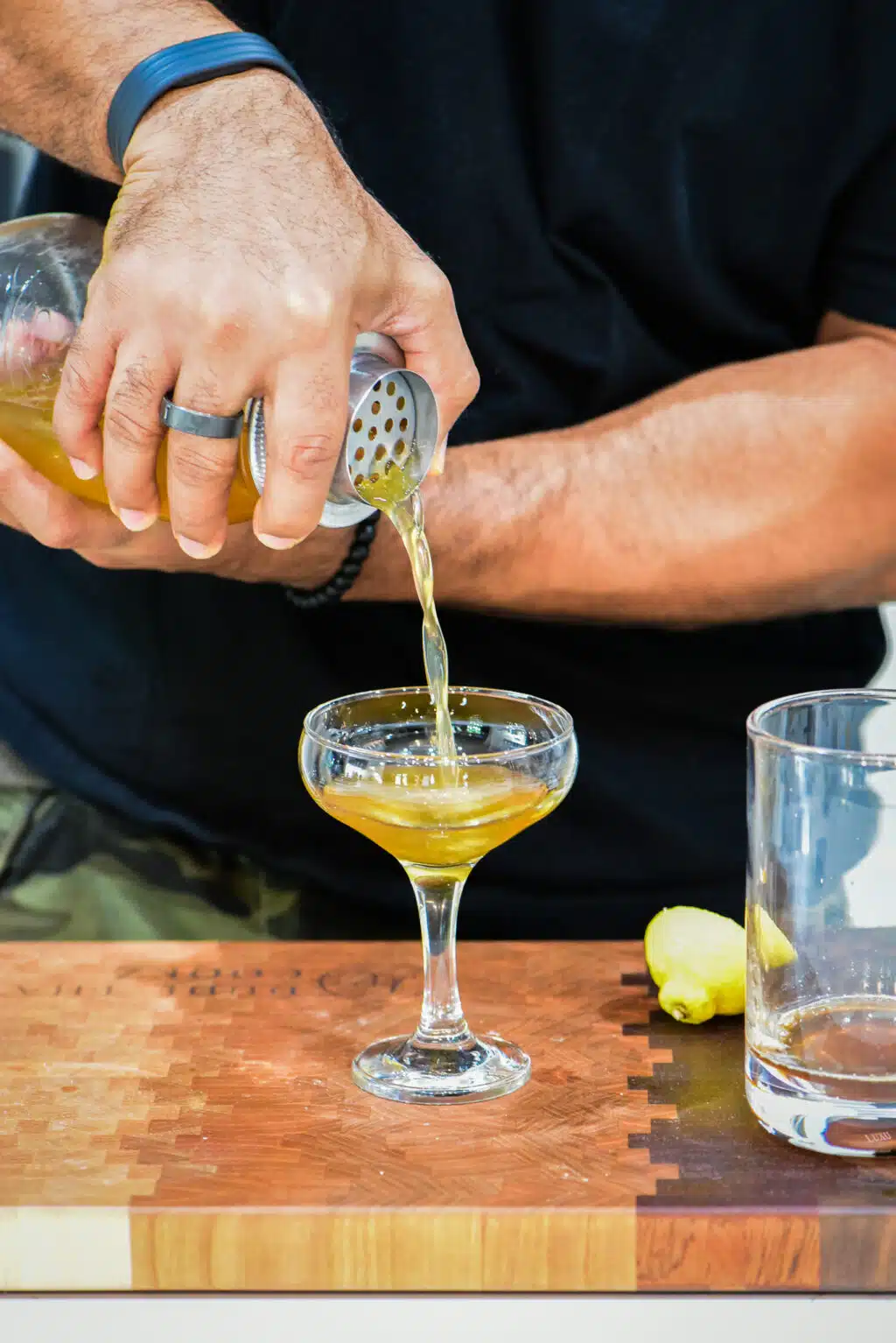 Pouring cocktail into a chilled coupe glass