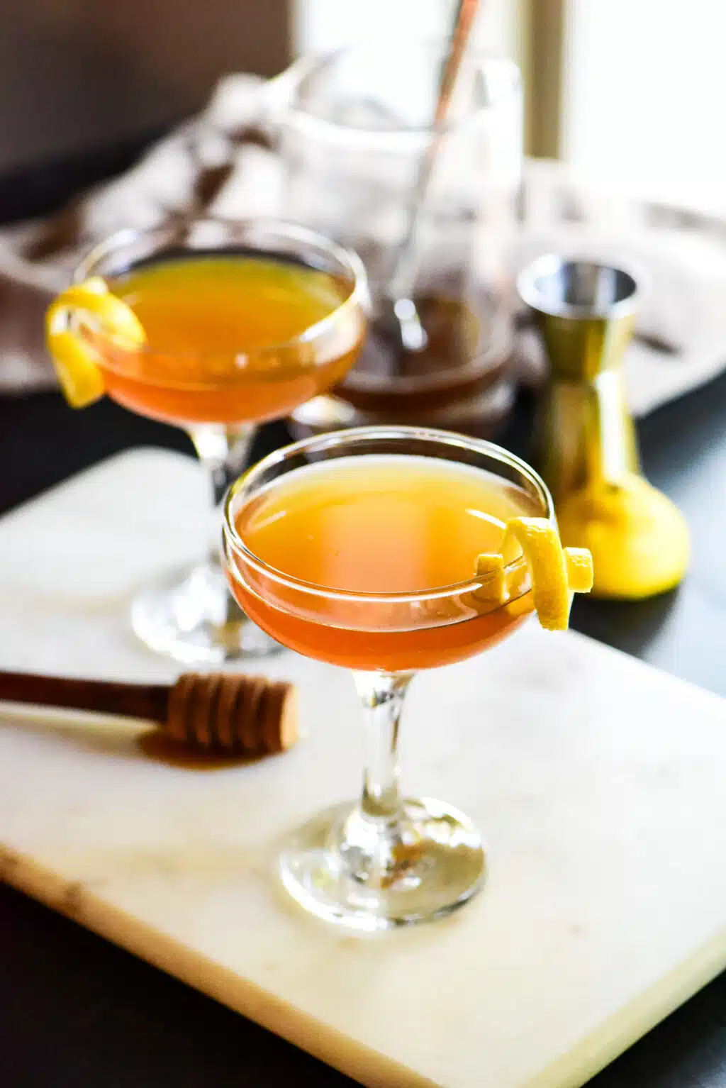 Two Gin Honey Bee cocktails garnished with lemon peels
