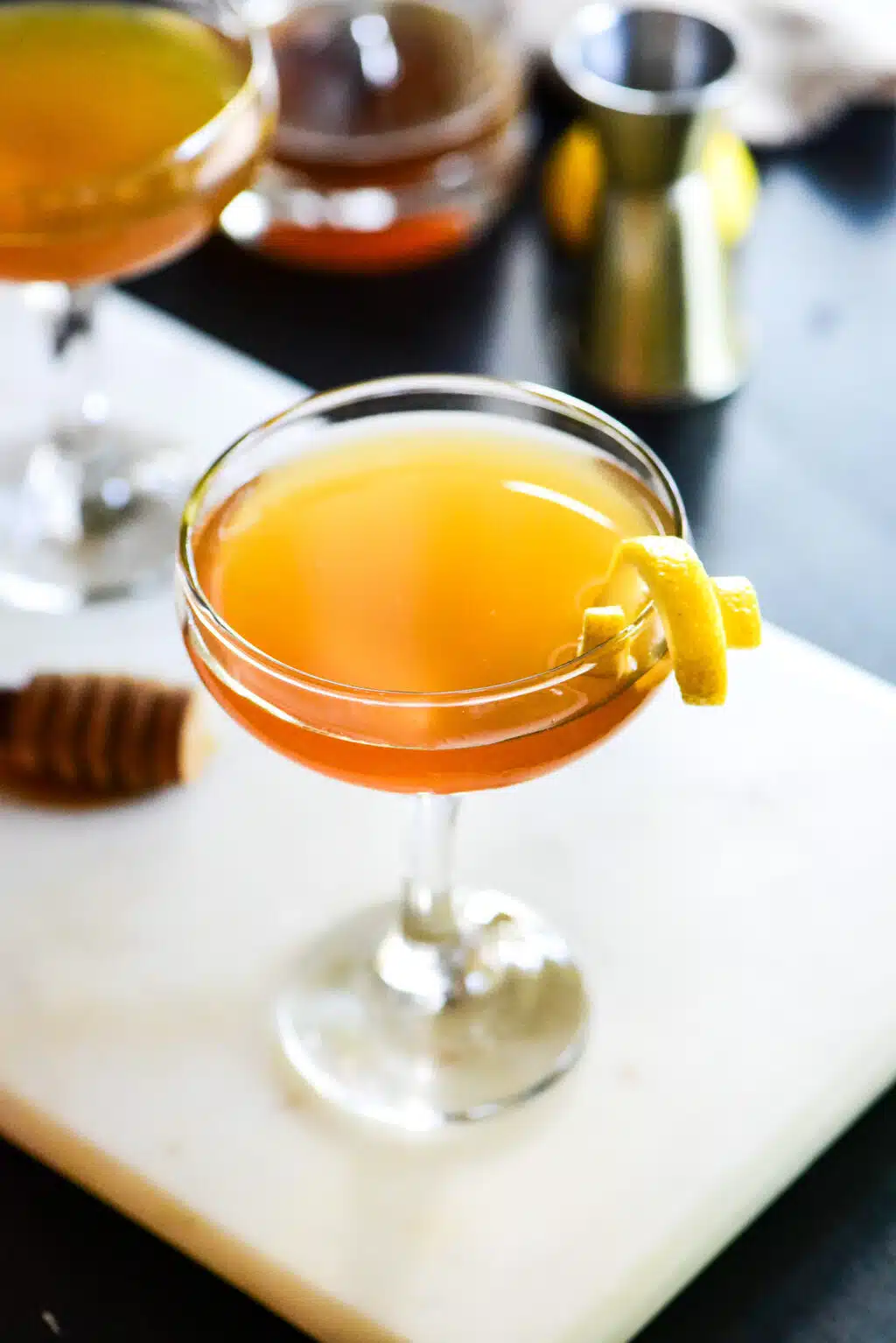 gin honey bee cocktail served in a glass with a lemon peel