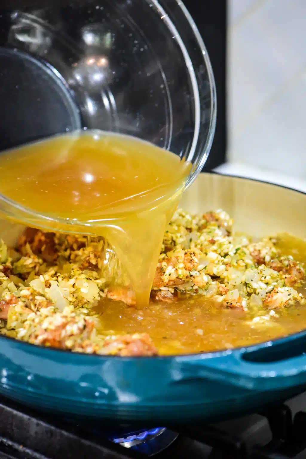 pouring the chicken stock in the Dutch oven